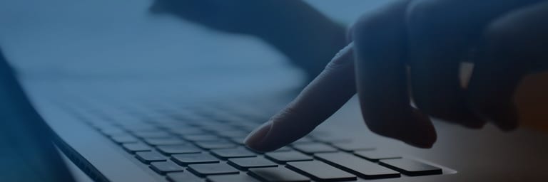 Close-up of a hand pressing a key on a laptop keyboard — accessing the client portal