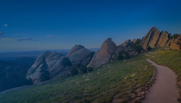 Devil's Backbone-style red rock formations above Loveland, Colorado, with a winding trail and the Front Range in the distance
