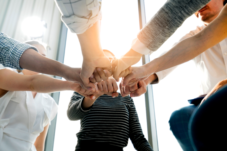 A team stacking hands together in a sunlit office