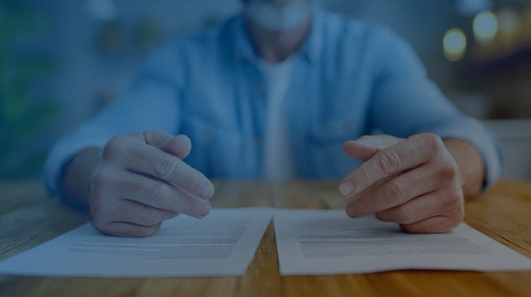 A person at a desk reviewing two contracts side by side